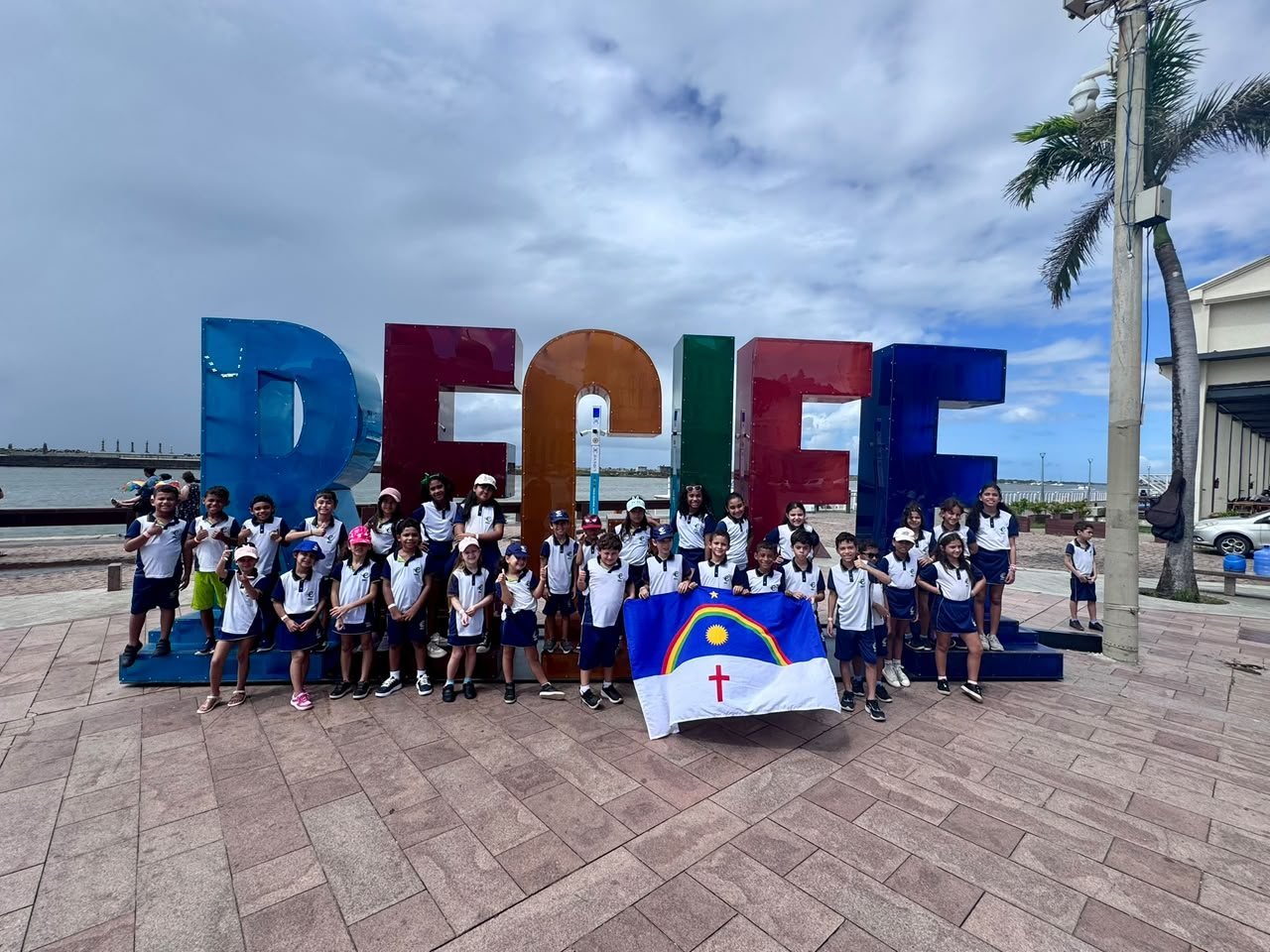 Turma do Fundamental I no letreiro do Recife com a bandeira de Pernambuco